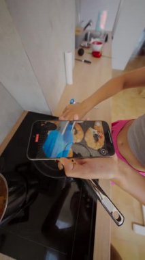 Canlı ve canlı bir mutfak sahnesi yemek pişirme sanatını resmediyor ve özel anları akıllı telefon kullanarak yakalıyor.