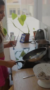 Parlak bir mutfakta neşeli bir şekilde yemek pişiren genç bir insan enerji ve yaratıcılık dolu canlı bir atmosfer sergiliyor.