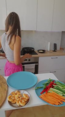 Bir kadın taze sebzeler ve karideslerle canlı bir yemek hazırlıyor, aşçılık sanatını ve aşkını sergiliyor.