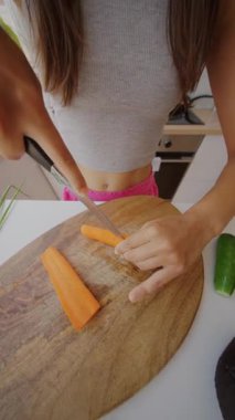 Neşeli bir mutfakta taze, canlı havuçları doğramak, renkli ve sağlıklı bir salata tabağına hazırlanmak.