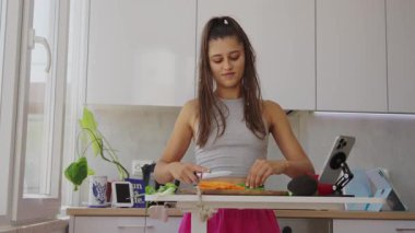 Genç bir kadın açık bir mutfakta taze malzemeler hazırlıyor. Sağlıklı yemek yapma becerilerini sergiliyor.