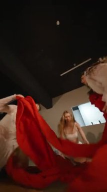 Sanatsal bir alanda büyüleyici bir dans gösterisi hareketi, zarafet ve canlı kırmızı kumaş.