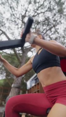 Formda bir kadın, güzel bir açık hava ortamında egzersiz malzemesi kullanarak enerjik bir şekilde antrenman yapar.