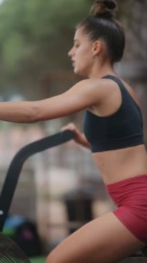 Odaklanmış bir birey, açık havada şık ve rahat bir şekilde kürek çekme makinesi üzerinde gayretli bir şekilde egzersiz yapar.