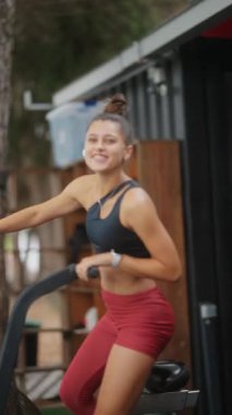 Genç bir kadın dışarıda durgun bir bisikletle heyecan verici bir egzersiz yapıyor.