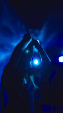 Büyüleyici bir siluet, büyüleyici ve parlak mavi ışık efektleriyle aydınlatılmış yetenekli bir sanatçının.