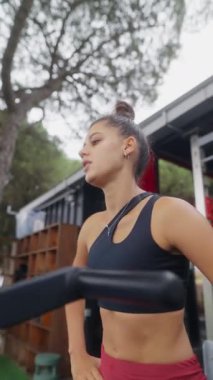 Modayı takip eden bir açık hava ortamında kararlı bir kadın yoğun bir kardiyo çalışması yapıyor.