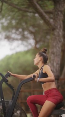 Genç bir kadın, bereketli ağaçlar ve güzel doğa ile çevrili bir hava aracının üzerinde enerjik bir şekilde bisiklet sürüyor.