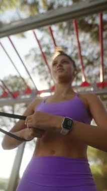 Canlı bir açık hava ortamında direnç bantları kullanan çekici ve etkili bir fitness rutinine katılıyoruz.