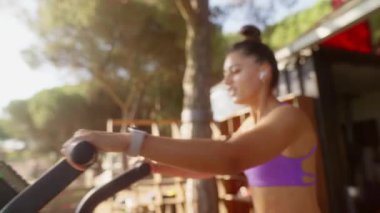 Kendini adamış bir fitness meraklısı açık havada eliptik bir makine üzerinde egzersiz yapıyor ve sağlıklı bir yaşam tarzını kucaklıyor.