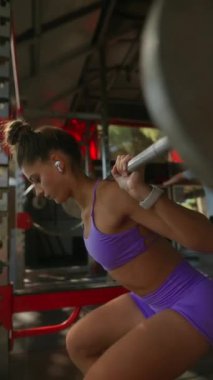 Odaklanmış bir birey, canlı bir spor salonunda çömelir. Güç ve kararlılık gösterir..