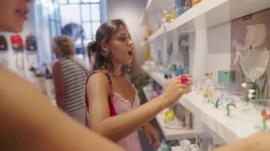 Genç bir kadın şık bir perakende mağazasında sergilenen güzel ve renkli camlara hayran.