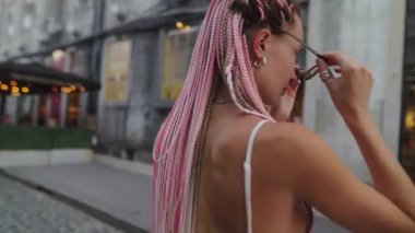 Eğlenceli pembe örgülü iki genç kadın neşeli ve renkli bir sokak manzarasının keyfini çıkarıyorlar.