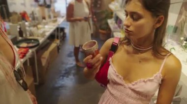 Bir kadın şık ve hareketli bir mağazada alışveriş yaparken bir dizi renkli ürünle mutlu mesut ilgilenir.