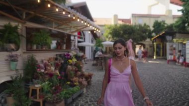 Canlı bir açık hava pazarı, hareketli aktiviteler, renkli çiçekler ve eğlenen genç bir kadın.