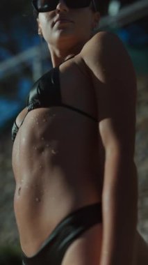 Büyüleyici bir model, modaya uygun ve şık bir mayo giyiyor, etrafa su damlacıkları saçarak kendine güveni yayıyor.