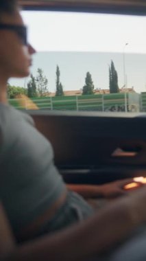 Bir kadın mutlu bir şekilde modern bir arabayla gezerken pencereden çarpıcı manzaralar yakalıyor.