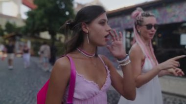 İki şık kadın neşe içinde çarpıcı, renkli sokak sanatlarıyla dolu canlı bir şehir ortamını keşfediyorlar.