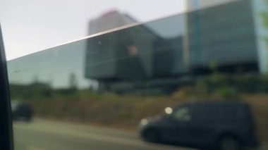 Dinamik bir şehir manzarası cama canlı bir şekilde yansıtılır, hareketli şehir hayatının yanında modern mimari sergilenir.