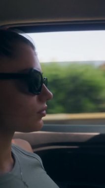 Huzurlu bir anda, genç bir kadın yolculuğunun tadını çıkarırken düşünceli bir şekilde arabanın camından dışarı bakar.