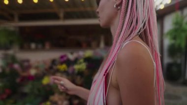 Benzersiz saç stilleri olan iki şık kadın renkli çiçekler ve enerjiyle dolu canlı bir pazarı keşfediyorlar.