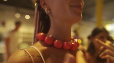 Tarz sahibi bireyler, modaya uygun ve davetkar bir butik ortam içinde bir dizi canlı kolye sergiliyorlar.