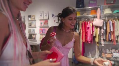 İki arkadaş, şık kıyafetler ve şık kıyafetlerle dolu canlı bir butikte alışveriş yaparken neşeli anların tadını çıkarıyorlar.