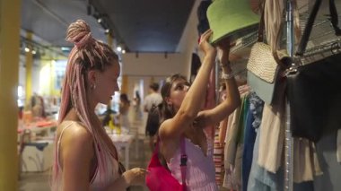 İki arkadaş bir butikte maceraya atılırlar, parlak şapkalar ve renkli aksesuarlar keşfederler.