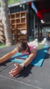 Bir kız, açık havada yoga minderinde spor yapıyor. Sağlık hizmetlerine kendini adamış..