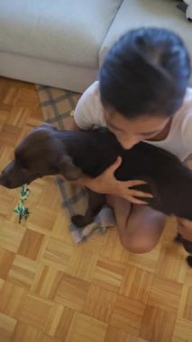 Evdeki oyun saatinde genç bir kadın ve köpeği arasında neşe dolu bir etkileşim meydana gelir.