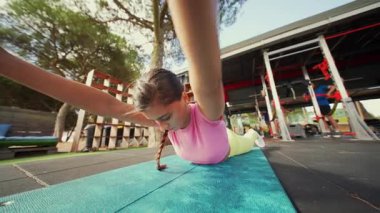 Canlı bir açık hava spor salonunda, neşeli bir genç kız aktif ve sağlıklı kalmak için spor yapıyor.