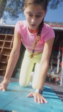 Kendini adamış ve odaklanmış genç bir kadın açık havada güzel bir ortamda spor yapmaya çalışıyor.