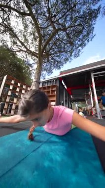 Genç bir kız, güneşli bir açık havada, renkli bir mindere etkileyici bir yoga pozu veriyor.