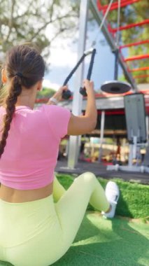 Formda ve kararlı bir birey, açık hava spor salonunda direniş bantları kullanıyor.