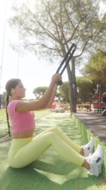 Kendini adamış bir fitness meraklısı güneşli bir açık hava ortamında aktif olarak direnç bandı eğitimi alıyor.