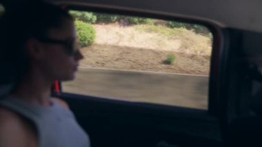 Bir kadın düşünceli bir şekilde pencereden dışarı bakar manzaralı bir araba yolculuğu sırasında, tamamen kendi düşüncelerinde kaybolur.