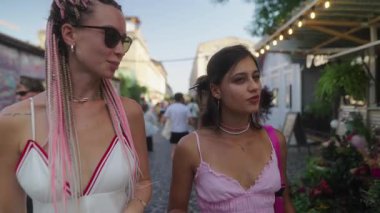 İki şık arkadaş canlı bir pazarda rahatça dolaşır, çevrelerindeki hayat dolu atmosferin tadını çıkarırlar.