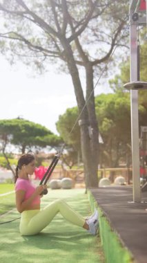 Bir kadın, çarpıcı ve pitoresk bir açık hava spor salonunda aktif olarak kablo egzersizleri yapar.