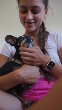 Şefkatli genç bir kadın, sevgili küçük köpeğiyle keyifli bir an geçirir, derin bağlarını gösterir.