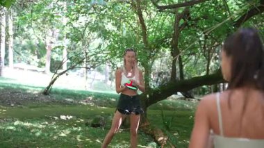 Güneşli bir günde, iki arkadaş, açık havanın canlı yeşilliklerinde raket oynarken eğlenirler.