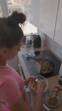 Genç ve yaratıcı bir aşçı, parlak ve modern bir mutfakta zevkli ve aromatik bir yemek pişirir.