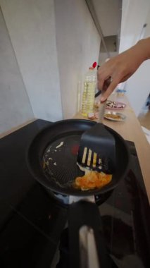 Tecrübeli bir aşçı, parlak, modern bir mutfakta çırpılmış yumurtaları ustalıkla çevirir.