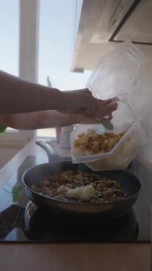 Lezzetli bir yemek için bir tava sotelenmiş sebzeye pilav ekleyen biri.