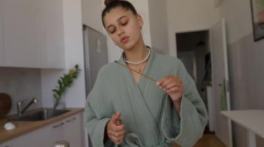 Huzurlu ve huzurlu bir sahne. Genç bir kadın. Samimi mutfağında sabah ritüelini gerçekleştiriyor.