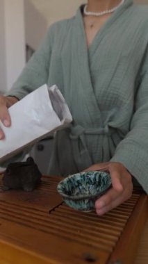 Huzurlu bir çay hazırlama sahnesi, zarif bir elin dekoratif bir kaseye gevşek çay dökmesi..