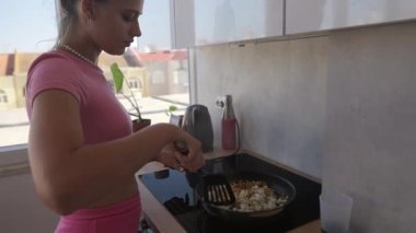 Bir kadın taze malzemeler kullanarak parlak ve çağdaş mutfağında lezzetli yemekler hazırlamakla meşgul.