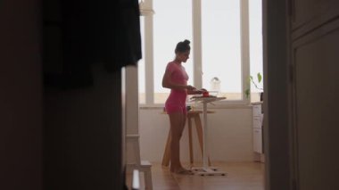 Parlak ve doğal ışıkla dolu modern bir mutfakta genç bir kadın lezzetli yemekler hazırlamakla meşgul.