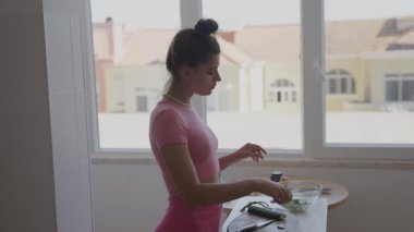 Bir kadın aydınlık, modern bir mutfakta verimli bir şekilde taze sebzeler hazırlar.