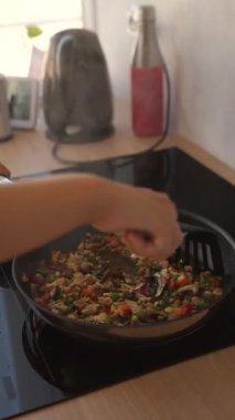 Sıcak tavada cızırdayan renkli ve aromatik bir karıştırıcı taze sebze ve protein karışımı sergiliyor.