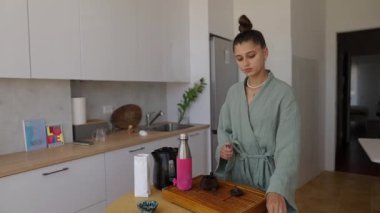 Bir birey düşünceli bir şekilde bir fincan çay hazırlar, dikkatlerini ve mutfaktaki sakin atmosferi gösterir.